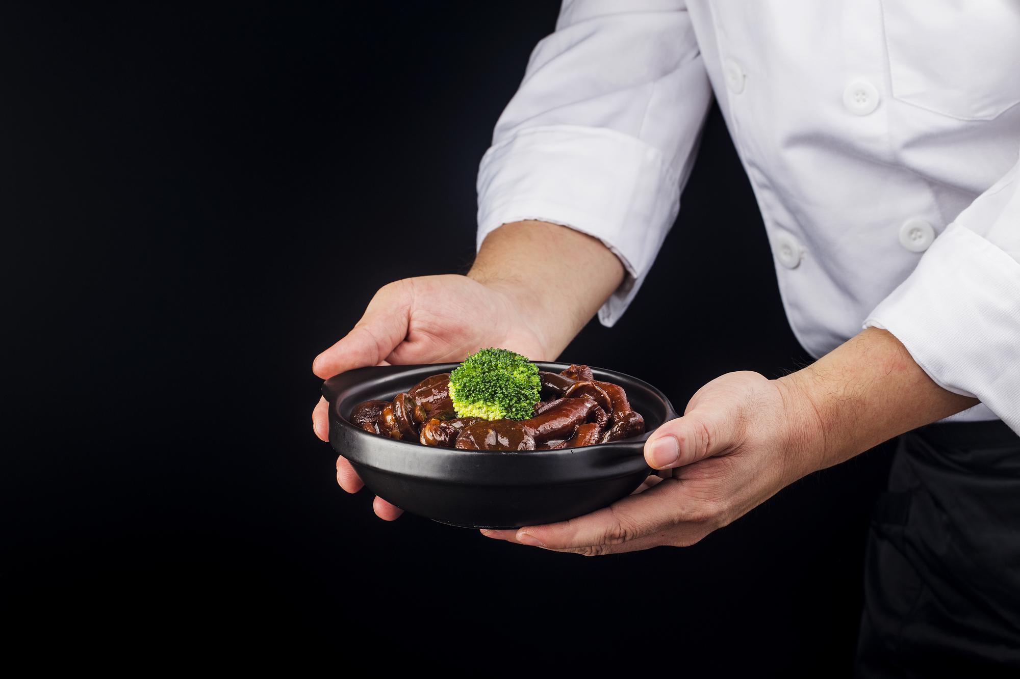 Chef plating a modern dish on a dark surface